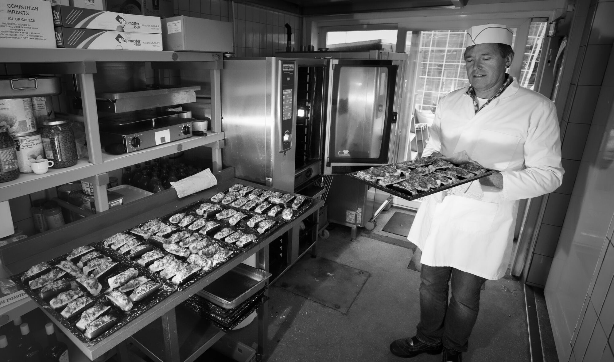 Un cuisinier de la maison présente une plaque de plats préparés